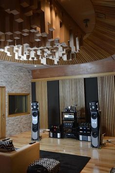 a living room filled with lots of furniture and sound equipment on top of a hard wood floor