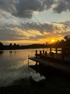 the sun is setting over a body of water with a dock in front of it