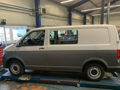 a grey van is parked in a garage with other cars and tools on the floor