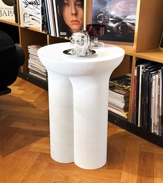 a white table with two vases on top of it in front of bookshelves