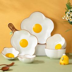 three eggs are sitting in white bowls on a table next to a rubber ducky toy