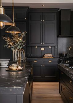 a kitchen with black cabinets and marble counter tops, gold accents on the handles and pulls