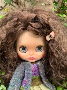 a close up of a doll with long hair and blue eyes wearing a purple dress