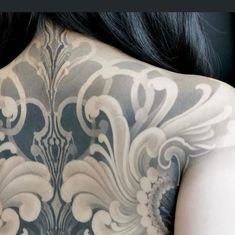 the back of a woman's body covered in black and white tattoos