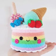 a hand holding a crocheted cupcake with an ice cream cone on top