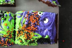 there is a piece of cake decorated with green and purple icing, sprinkles and eyes