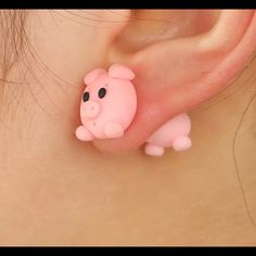 a close up of a person's ear with a small pink pig on it