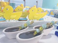 some little yellow ducks are sitting in the bathtub with soaps on them and candy