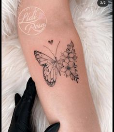 a woman's leg with a butterfly and flowers tattoo on the left side of her arm