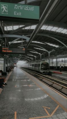 people sitting on benches at an airport waiting for the train to come down the track