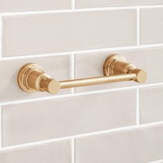 a gold towel bar on a white brick wall