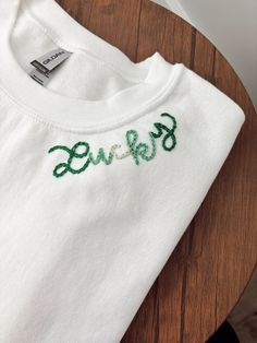 a white t - shirt with the word love embroidered on it sitting on a wooden table