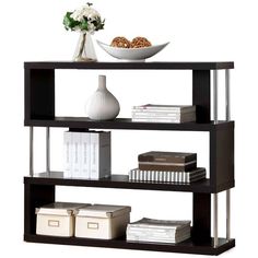 a book shelf with books, magazines and a bowl of flowers on top of it