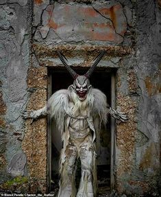 a man dressed as a demon standing in front of a doorway