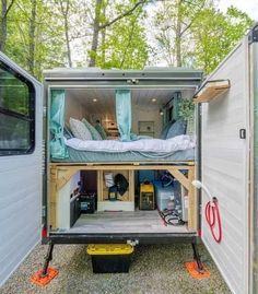 the inside of an rv with its door open to reveal a bed and storage area