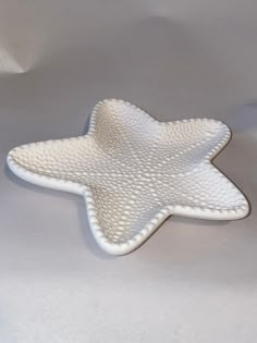 a white ceramic star dish sitting on top of a white tablecloth covered flooring