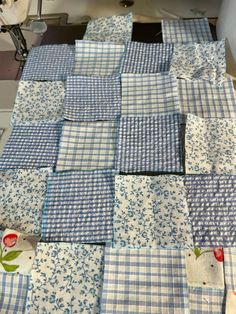 blue and white checkered quilts are laid out on a sewing machine in the process of being sewn