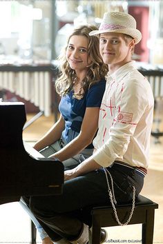 a young man and woman sitting at a piano