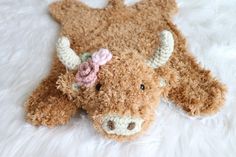 a stuffed animal laying on top of a white fur covered floor with a pink flower in it's ear