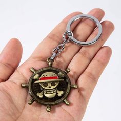 a hand holding a key chain with a skull and crossbones on it