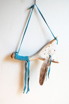 a wall hanging made out of antlers with feathers and beads on it's sides