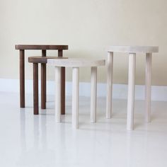 three small tables sitting next to each other on a white floor in front of a wall