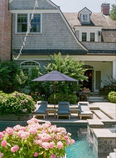 a house with a pool and patio furniture in the front yard, surrounded by flowers