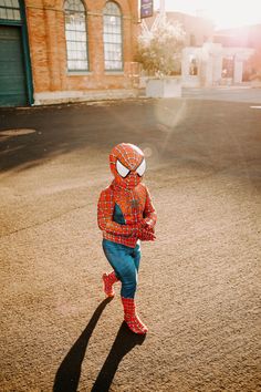 a little boy in a spiderman costume is running