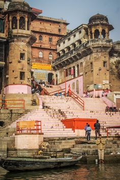 some people are standing on steps near the water and boats in front of an old building