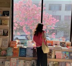 a woman standing in front of a window looking at books