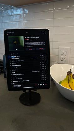 a computer monitor sitting on top of a counter next to a bowl of bananas