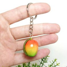 a hand holding an apple shaped keychain in it's left palm area