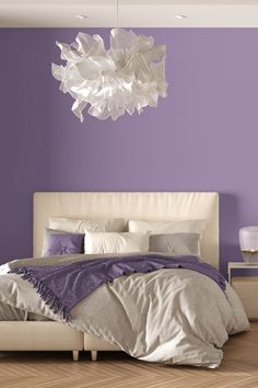 a bedroom with purple walls and a white bed in front of a large chandelier