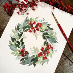 a watercolor painting of a wreath with red berries and green leaves on white paper