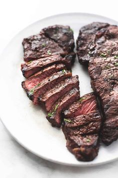 sliced steak on a white plate with green garnish