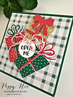 an open me christmas card with presents on it and a green plant in the background