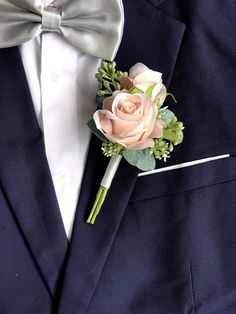 a boutonniere with pink roses and greenery on the lapel of a man in a tuxedo