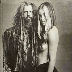 a man with long hair standing next to a woman