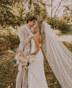 a bride and groom are standing in the woods with their veil blowing in the wind