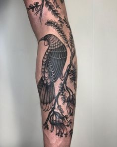 a tattoo on the leg of a man with a bird sitting on a tree branch