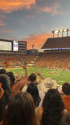 a football stadium filled with lots of people watching the game at sunset or sunrise time