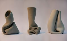 three vases sitting side by side on a white surface, one is shaped like a woman's legs