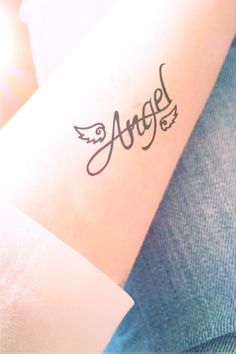 an arm with the word angel written on it and wings in black ink, sitting next to a person's arm