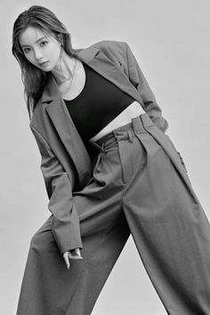 a woman in grey pants and a black top is posing for a magazine cover photo