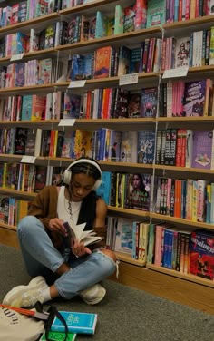 a woman sitting on the floor in front of a bookshelf filled with books