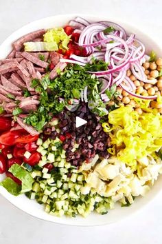 a salad with meat, beans, lettuce and tomatoes in a white bowl