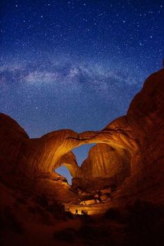 the night sky is filled with stars and light up rock formations that are illuminated by lights