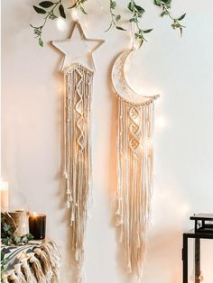 two wall hangings decorated with lights and greenery next to a lit candle on a table