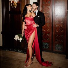 a man in a tuxedo kissing a woman wearing a red dress and high heels