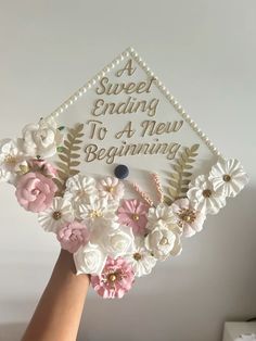 someone is holding up a graduation cap with flowers on the front and side, which reads sweet ending to a new beginning